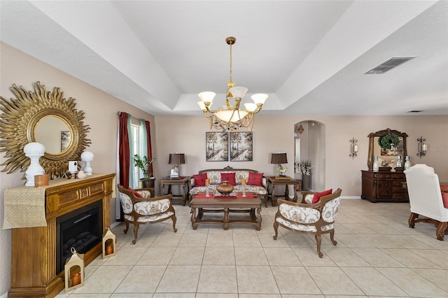 living room featuring visible vents, a tray ceiling, light tile patterned flooring, arched walkways, and a notable chandelier