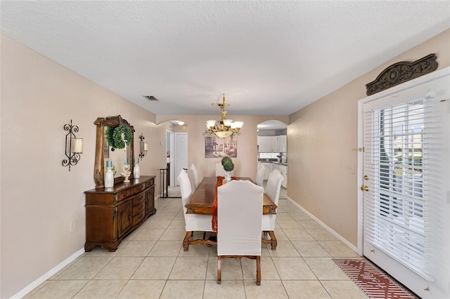 dining area featuring an inviting chandelier, light tile patterned floors, visible vents, and arched walkways