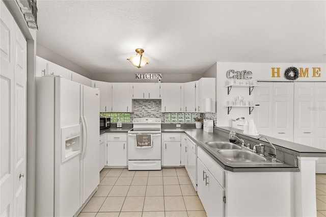 kitchen with tasteful backsplash, dark countertops, light tile patterned floors, white appliances, and white cabinetry