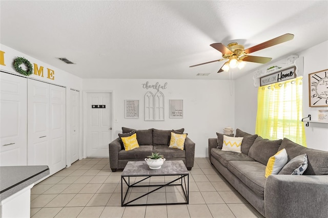 living area with visible vents, a textured ceiling, light tile patterned flooring, and a ceiling fan