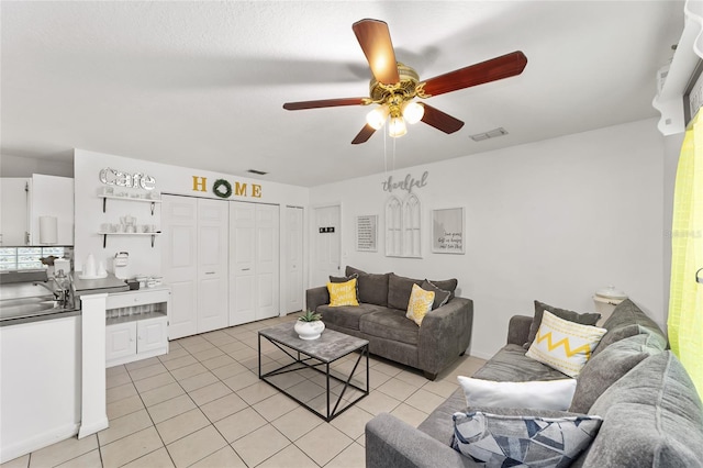 living room with light tile patterned flooring, visible vents, and a ceiling fan