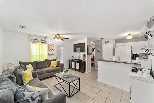 living area featuring light tile patterned flooring, visible vents, baseboards, and a ceiling fan