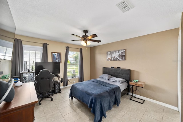 bedroom with ceiling fan, baseboards, visible vents, and a textured ceiling