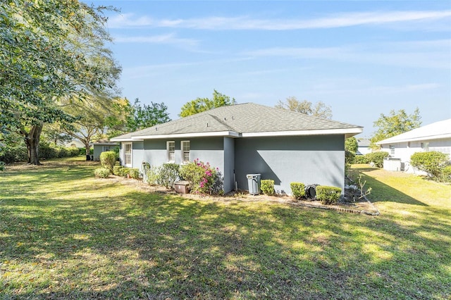 rear view of property featuring a lawn and stucco siding