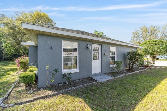 exterior space with stucco siding and a front yard