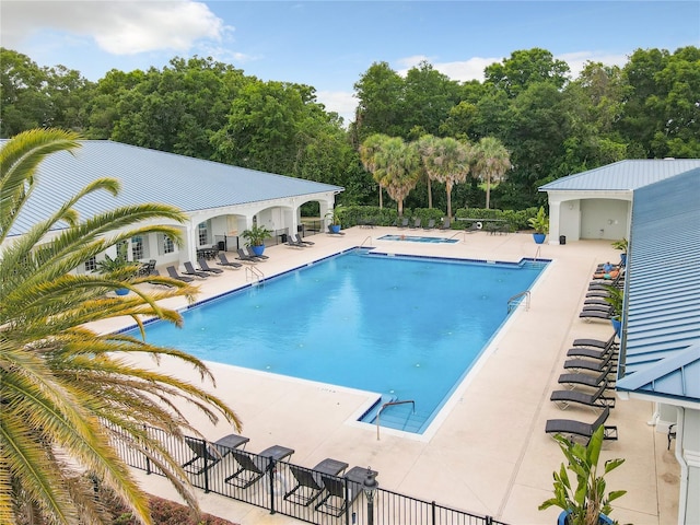 community pool featuring a patio, fence, and a hot tub