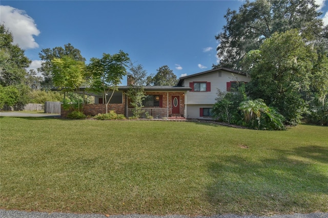 tri-level home with a front lawn, brick siding, covered porch, and a chimney