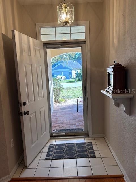 foyer with a chandelier, light tile patterned floors, and baseboards