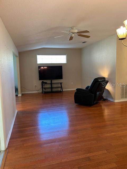 living area with lofted ceiling, baseboards, a ceiling fan, and wood finished floors