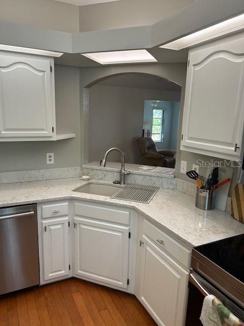 kitchen with stainless steel appliances, arched walkways, wood-type flooring, and a sink