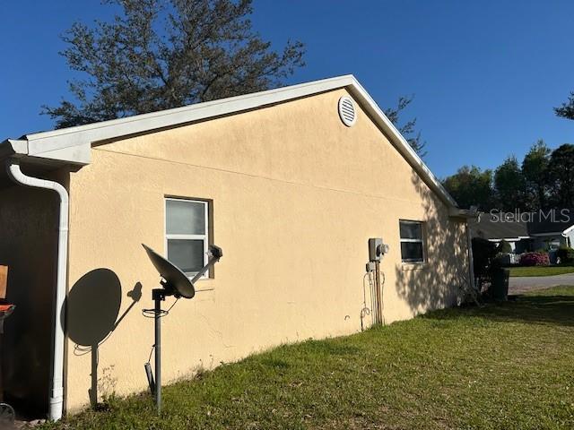 view of side of property featuring a yard and stucco siding