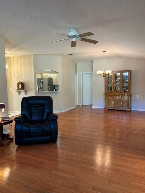 living room featuring hardwood / wood-style floors, ceiling fan with notable chandelier, and baseboards