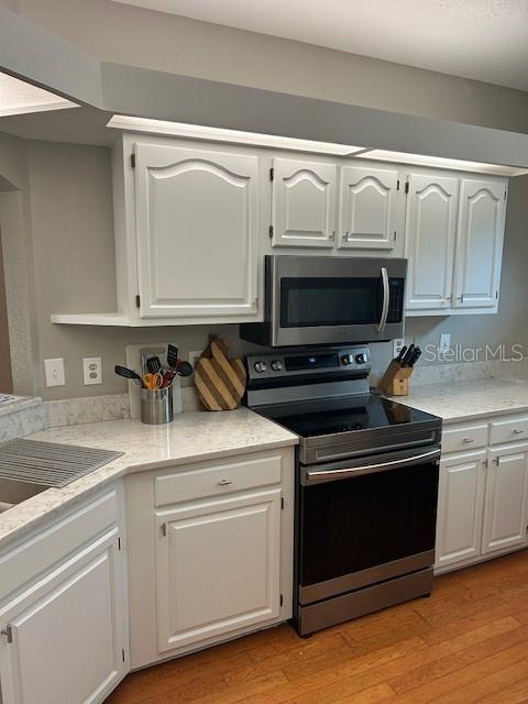 kitchen featuring white cabinetry, light countertops, appliances with stainless steel finishes, and light wood-style floors