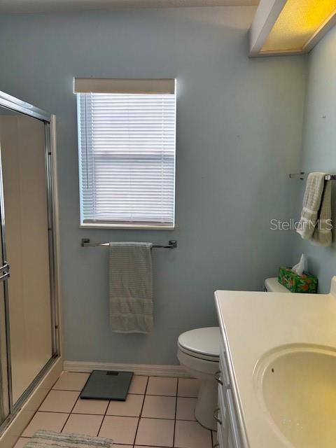bathroom featuring a shower stall, vanity, toilet, tile patterned floors, and baseboards