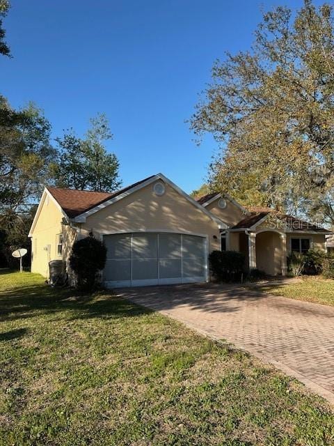 ranch-style house with an attached garage, a front yard, and decorative driveway