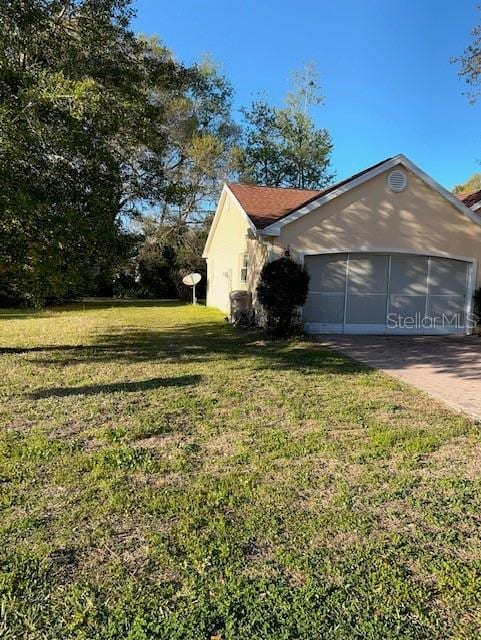 view of side of property featuring an attached garage, a lawn, and concrete driveway