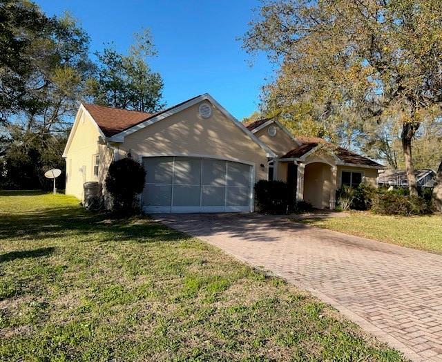 view of front of house featuring a garage, a front yard, stucco siding, and decorative driveway