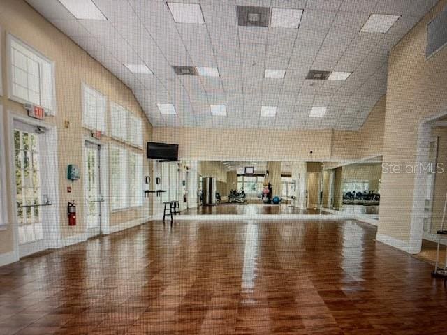 workout room featuring a paneled ceiling, baseboards, and wood finished floors