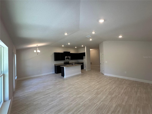 4528 SW 90th Lane Rd, Ocala, FL 34476 - kitchen featuring open floor plan, stainless steel microwave, dark cabinets, vaulted ceiling, and a textured ceiling