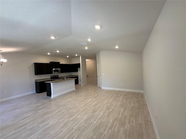 4528 SW 90th Lane Rd, Ocala, FL 34476 - kitchen featuring appliances with stainless steel finishes, open floor plan, dark cabinets, baseboards, and light wood finished floors