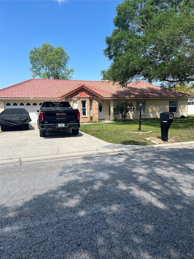 view of front of property featuring a front lawn, a tiled roof, concrete driveway, and an attached garage