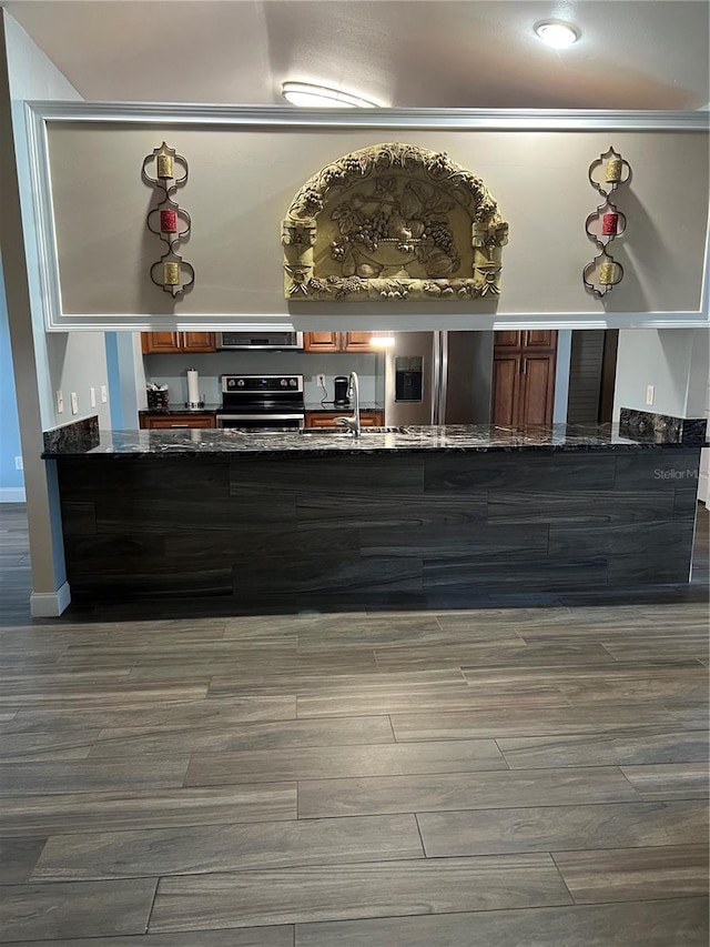 kitchen featuring refrigerator with ice dispenser, electric stove, a peninsula, and dark stone counters