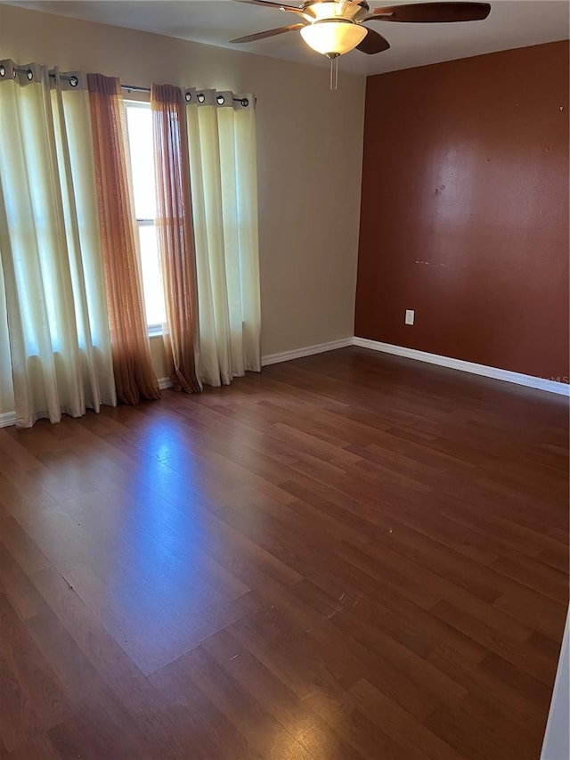 empty room featuring baseboards, wood finished floors, and ceiling fan