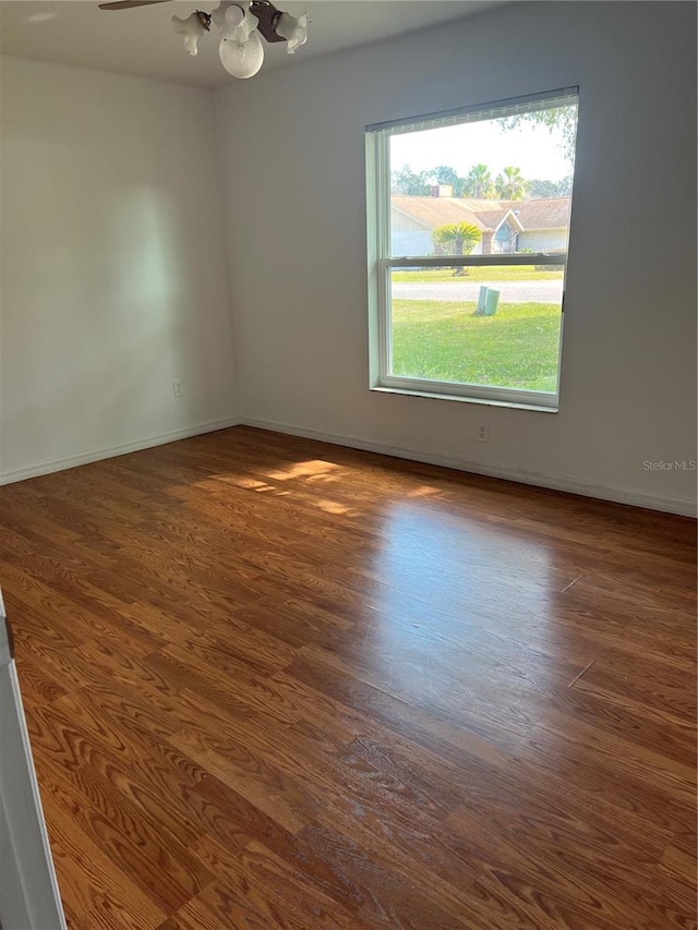 empty room featuring baseboards, an inviting chandelier, and wood finished floors