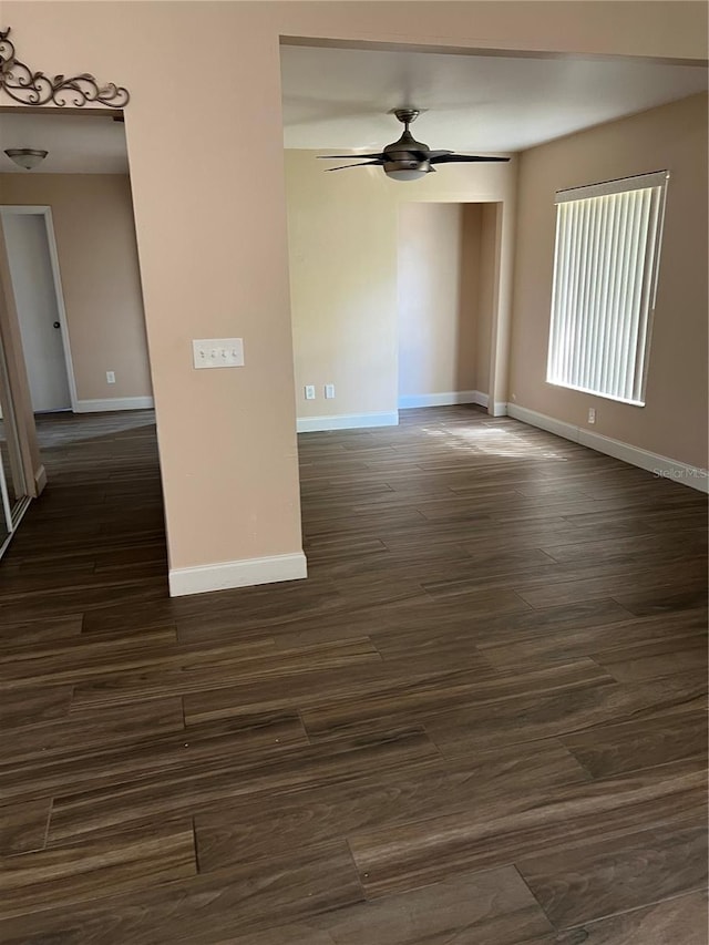 unfurnished room featuring baseboards, ceiling fan, and dark wood-style flooring
