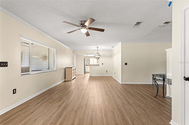 10980 SW 62nd Avenue Rd, Ocala, FL 34476 - unfurnished living room featuring visible vents, ornamental molding, ceiling fan with notable chandelier, light wood-style flooring, and a textured ceiling
