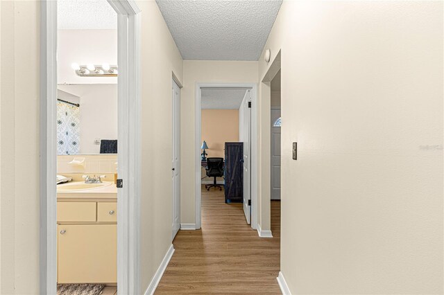 10980 SW 62nd Avenue Rd, Ocala, FL 34476 - corridor featuring a textured ceiling, light wood-type flooring, baseboards, and a sink