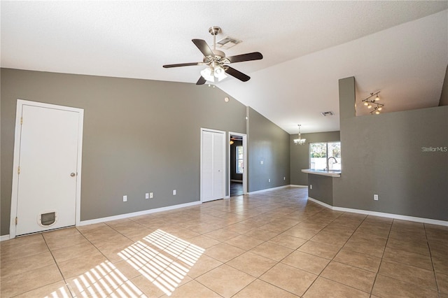 empty room with light tile patterned floors, visible vents, ceiling fan with notable chandelier, and lofted ceiling