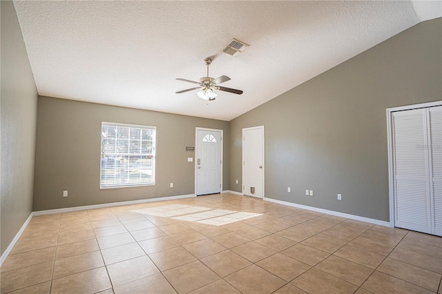 interior space with lofted ceiling, light tile patterned floors, a ceiling fan, and visible vents