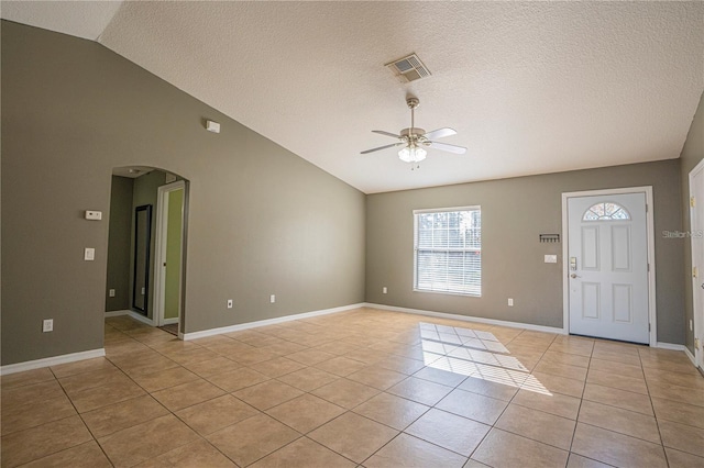 foyer entrance featuring visible vents, vaulted ceiling, light tile patterned floors, arched walkways, and a ceiling fan