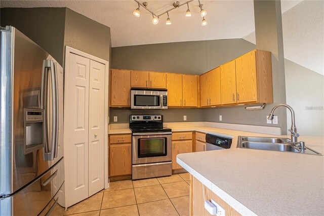 kitchen with light tile patterned floors, lofted ceiling, a sink, stainless steel appliances, and light countertops