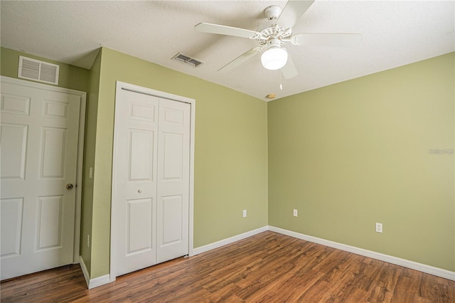 unfurnished bedroom with a closet, visible vents, baseboards, and wood finished floors