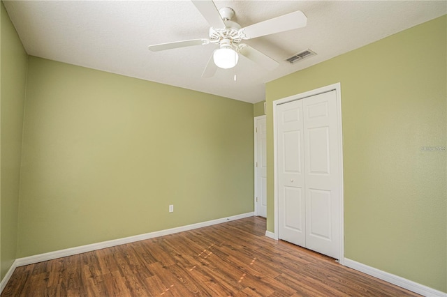 unfurnished bedroom with visible vents, baseboards, a closet, and wood finished floors