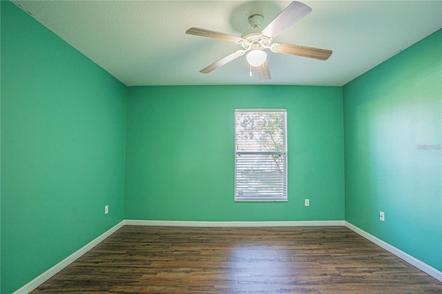 spare room with dark wood-type flooring, baseboards, and ceiling fan