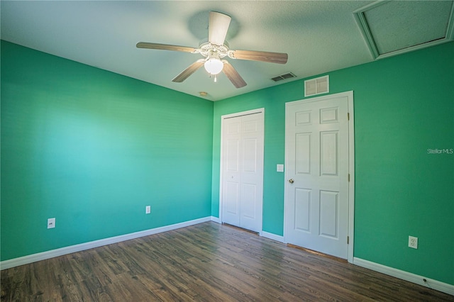 unfurnished bedroom featuring visible vents, baseboards, dark wood-type flooring, and a closet