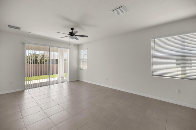 tiled spare room featuring a ceiling fan, visible vents, and a healthy amount of sunlight