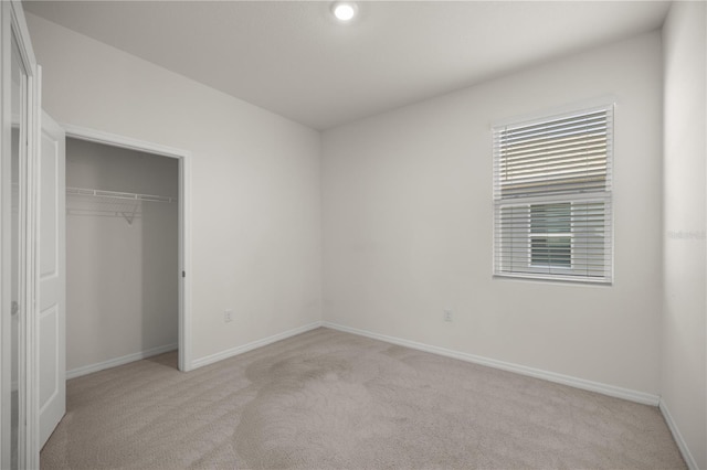 unfurnished bedroom with light colored carpet, baseboards, and a closet