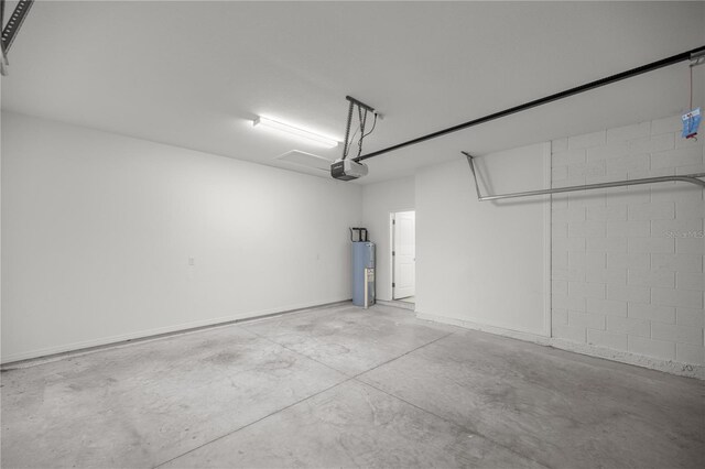 garage with water heater, a garage door opener, and concrete block wall