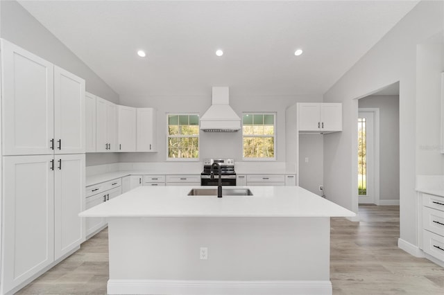 760 NE 152nd Ter, Williston, FL 32696 - kitchen with lofted ceiling, a kitchen island with sink, a sink, custom range hood, and white cabinets