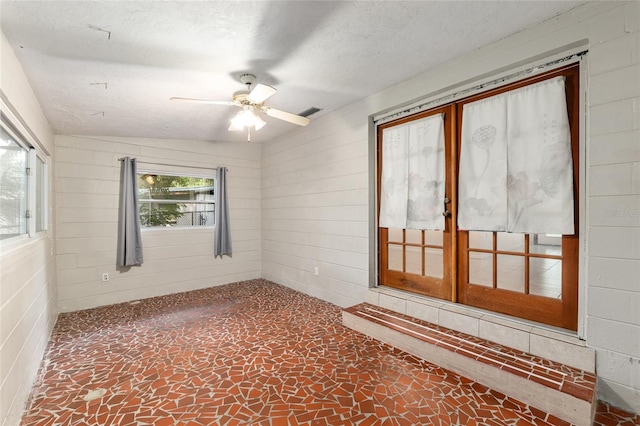 3910 SE 14th Ter, Gainesville, FL 32641 - spare room featuring a ceiling fan, stone floors, and wood walls