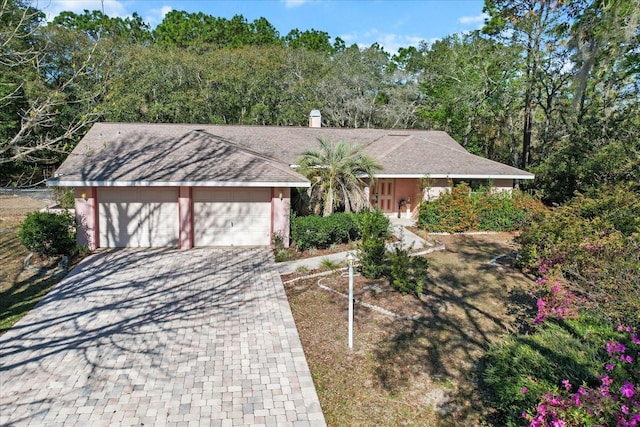 ranch-style house featuring stucco siding, a garage, driveway, and a shingled roof