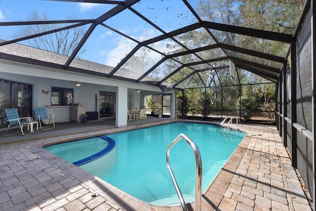 view of pool featuring a lanai, a pool with connected hot tub, and a patio