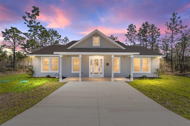 791 NE 150th Ave, Williston, FL 32696 - view of front of home with stucco siding, covered porch, a front lawn, and a shingled roof