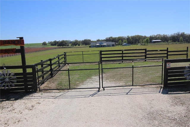 view of gate featuring a rural view, a yard, and fence