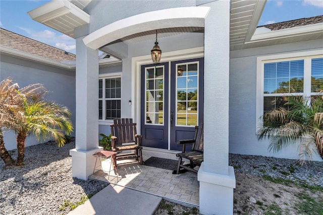 view of exterior entry featuring covered porch and stucco siding