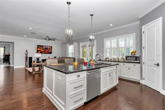 kitchen with plenty of natural light, ornamental molding, dark wood finished floors, appliances with stainless steel finishes, and a sink